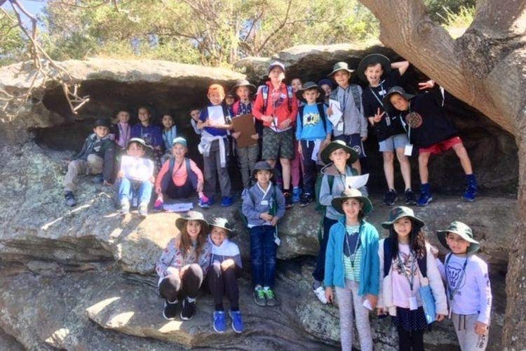A class group of students posing for a picture from within a cut out in the sandstone at Waverton, NSW.